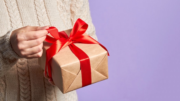 Persona in possesso di un contenitore di regalo di Natale o Capodanno con un nastro rosso