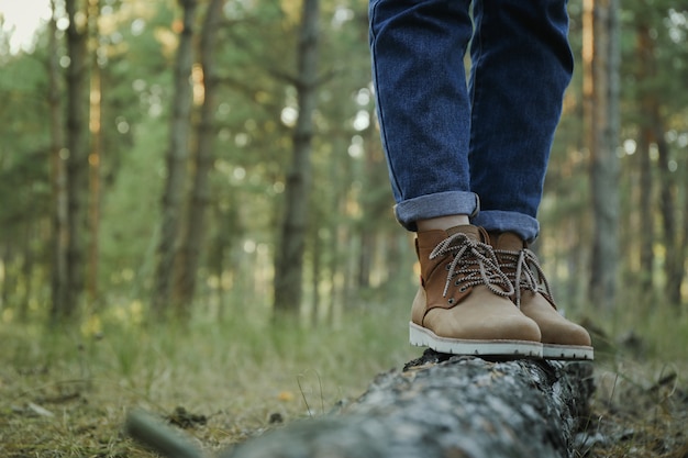 Persona in stivali e jeans sul tronco, spazio per il testo