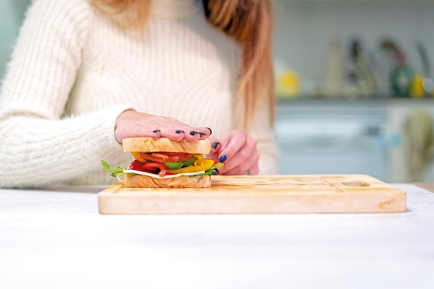 Persona irriconoscibile che cucina un panino alle verdure in cucina a casa finendo di prepararlo