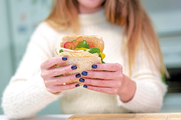 Persona irriconoscibile che cucina un panino alle verdure in cucina a casa finendo di prepararlo