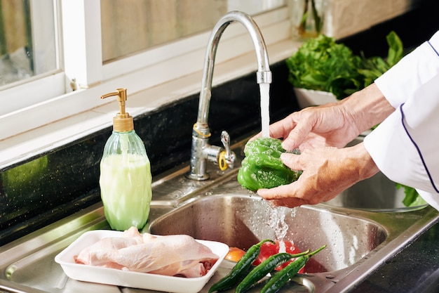 Persona matura che risciacqua le verdure