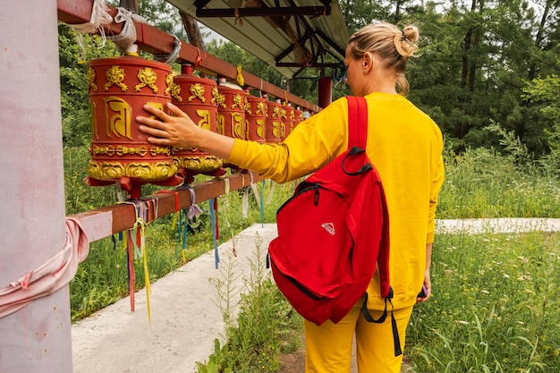 Persona pellegrina donna che tocca girando la ruota di preghiera buddista nella preghiera del monastero buddista