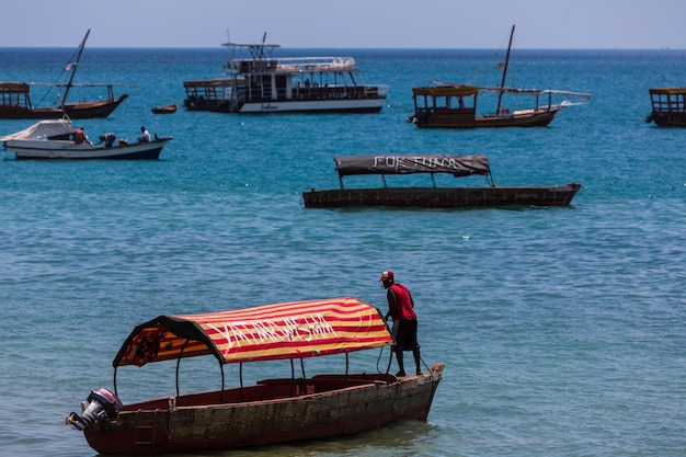 Persona sulla barca e molte barche nell'oceano. ZANZIBAR, TANZANIA