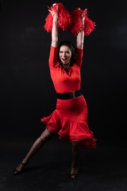 Persona vestito in posa danze giovane cheerleading attraente sfondo nero femminile rosso capelli scuri