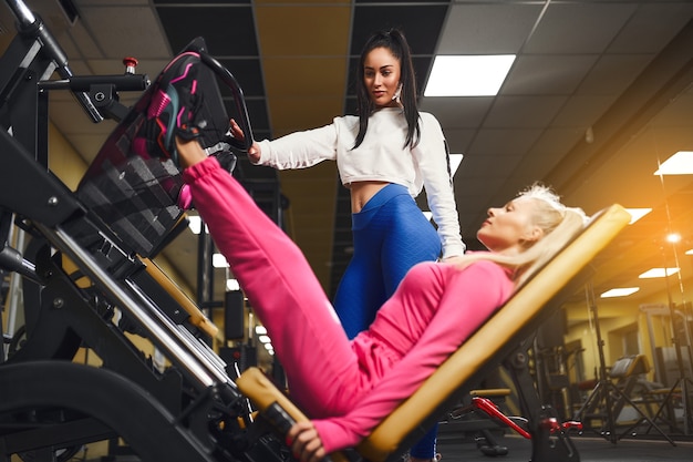 Personal trainer aiutando la donna a lavorare sull'apparato di formazione all'interno nel concetto di formazione di bodybuilding stile di vita sportivo centro fitness