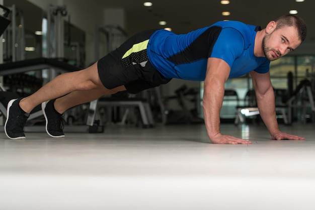 Personal Trainer facendo flessioni sul pavimento in palestra