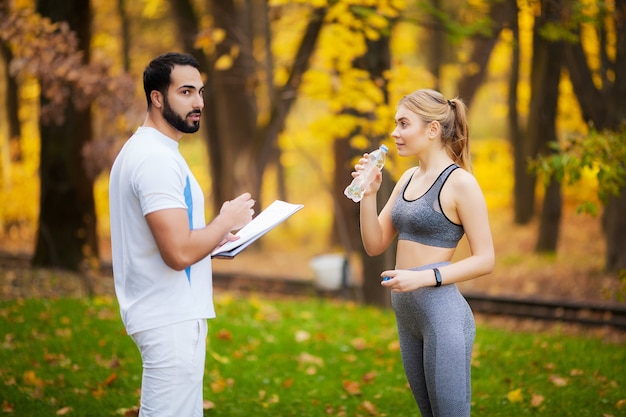 Personal trainer maschio che mostra i risultati alla sua cliente femminile.