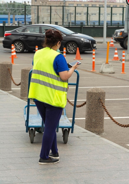 Personale di servizio della stazione ferroviaria con carrello per cose in attesa dei passeggeri