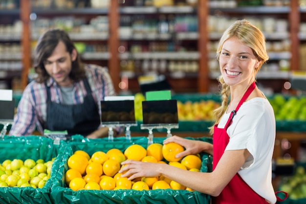 Personale femminile sorridente che controlla frutti nella sezione organica