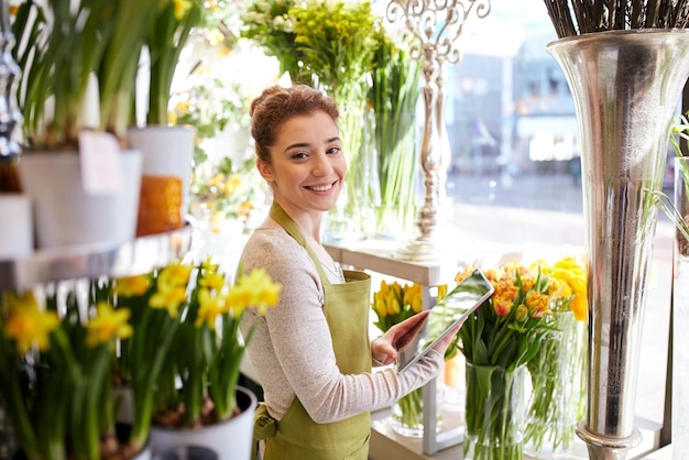 persone, affari, tecnologia, vendita e floristica e concetto - felice fiorista donna sorridente con computer tablet pc al negozio di fiori