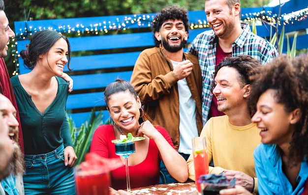 Persone alla moda millenarie che si divertono nel patio del cocktail bar alla moda