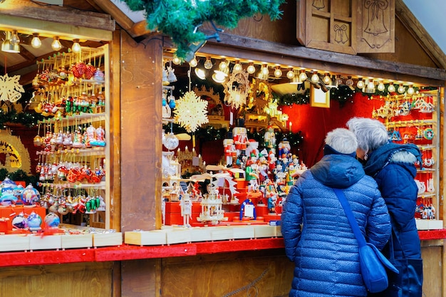 Persone allo stallo sul mercatino di Natale presso la Chiesa commemorativa dell'Imperatore Guglielmo in inverno a Berlino, Germania. Decorazione della Fiera dell'Avvento e bancarelle con oggetti di artigianato sul Bazaar.