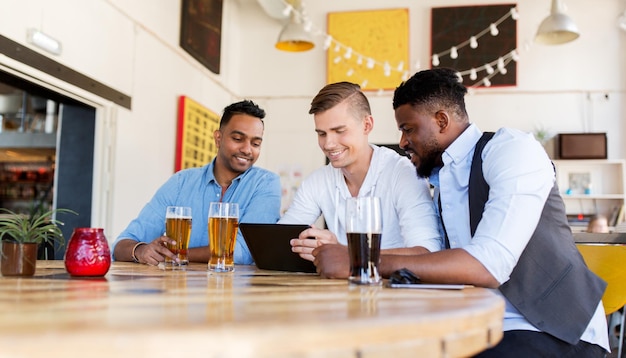 persone, amicizia maschile e concetto di tecnologia - amici felici con computer tablet pc che bevono birra al bar o al pub