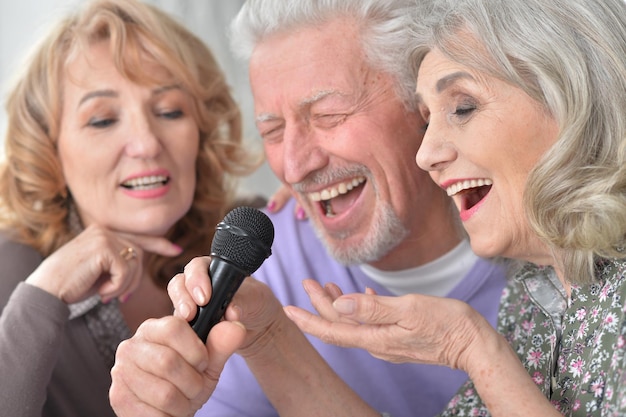 Persone anziane felici che cantano al karaoke con il laptop mentre bevono il tè