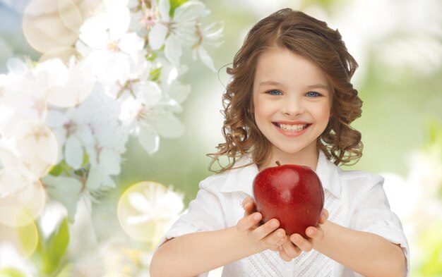 persone, bambini, mangiare sano e concetto di cibo- ragazza felice che tiene mela rossa su sfondo giardino estivo o primaverile