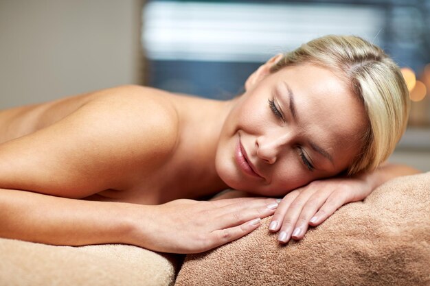 persone, bellezza, spa, stile di vita sano e concetto di relax - bella giovane donna sdraiata sul lettino da massaggio nella spa