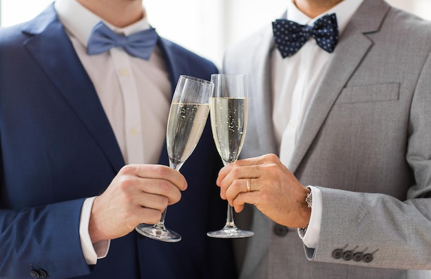 persone, celebrazione, omosessualità, matrimonio omosessuale e concetto di amore - primo piano di una coppia gay maschile sposata felice in giacca e cravatta che beve vino frizzante e bicchieri tintinnanti sul matrimonio