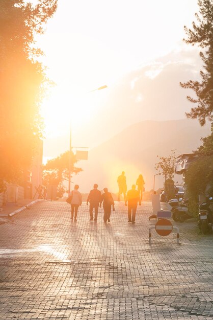 Persone che camminano lungo una strada asfaltata alla luce del sole