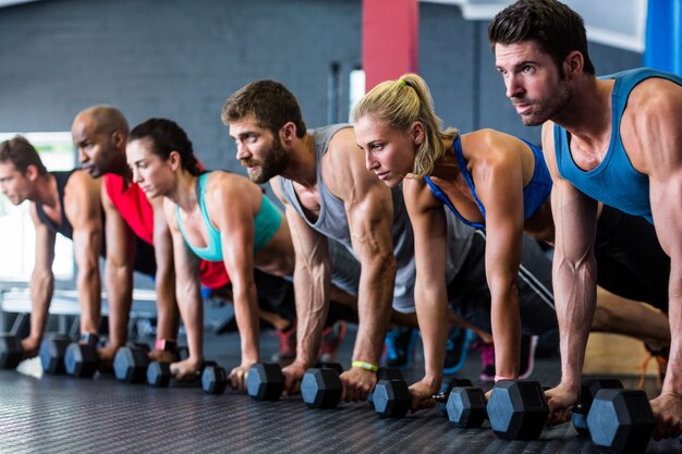 Persone che fanno flessioni con manubri in palestra