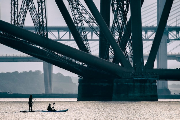 Persone che fanno paddleboard sul ponte sul fiume