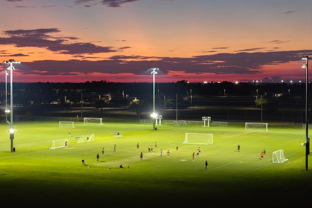 Persone che giocano a calcio in uno stadio pubblico illuminato al tramonto