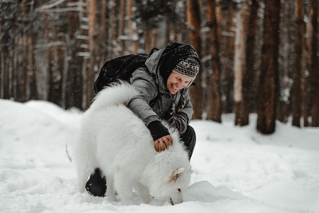Persone che giocano con il cane divertente nella foresta invernale
