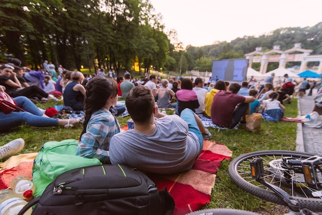 Persone che guardano film nel cinema all'aperto nel parco cittadino