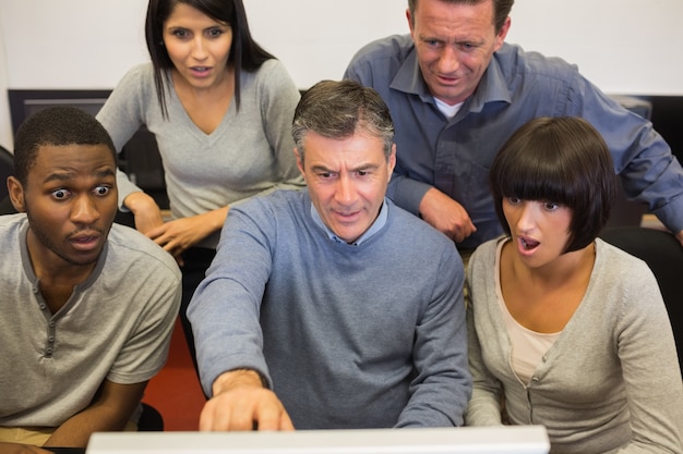 Persone che guardano il monitor del computer scioccato