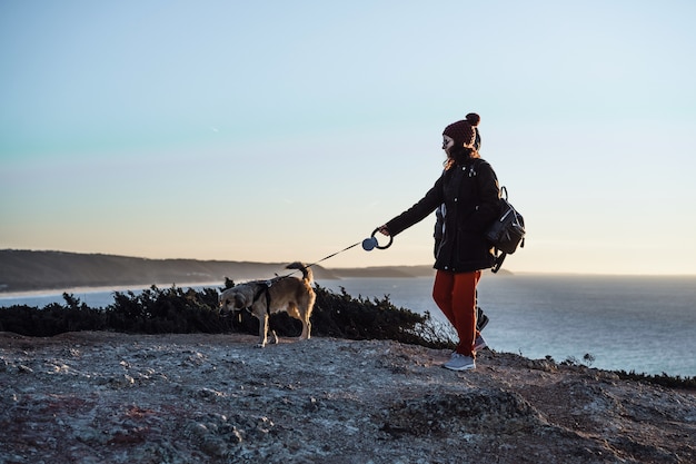 persone che guardano il tramonto su una roccia, un cane, lanciano un drone.