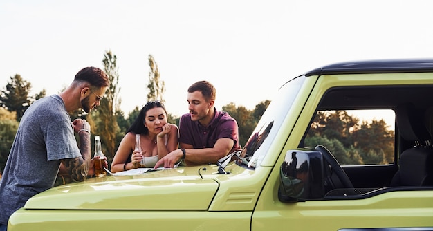 Persone che leggono la mappa che giace sul cofano dell'automobile