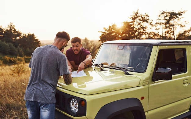 Persone che leggono la mappa che giace sul cofano dell'automobile