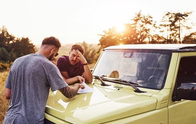 Persone che leggono la mappa che giace sul cofano dell'automobile