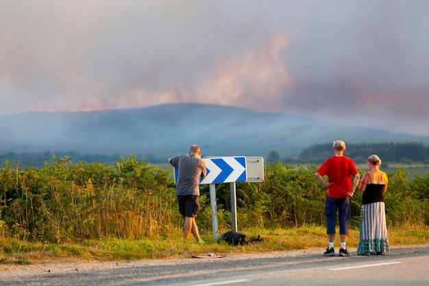 Persone che osservano da lontano l'incendio nei Monts d'Arree