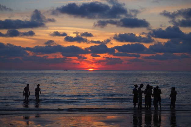 Persone che si bagnano sulla spiaggia al tramonto su una spiaggia thailandese (Koh Tao Island)