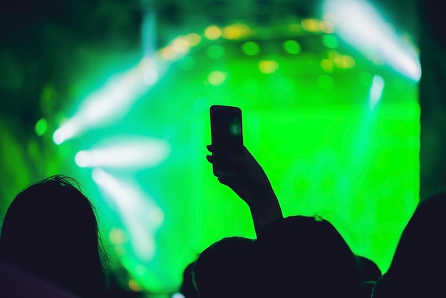 Persone che si godono un concerto rock e scattano foto con il cellulare al festival musicale