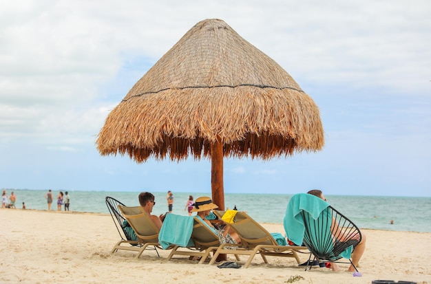 Persone che si rilassano su una spiaggia con un ombrellone di paglia