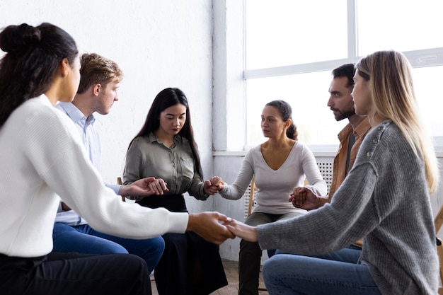 Persone che si tengono per mano in cerchio durante una sessione di terapia di gruppo