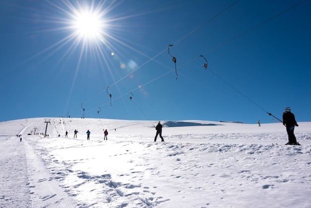 Persone che utilizzano impianti di risalita nella soleggiata giornata invernale sulla stazione sciistica