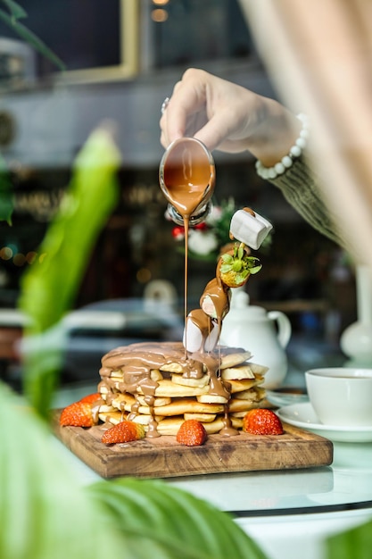 Persone che versano lo sciroppo su una pila di pancake