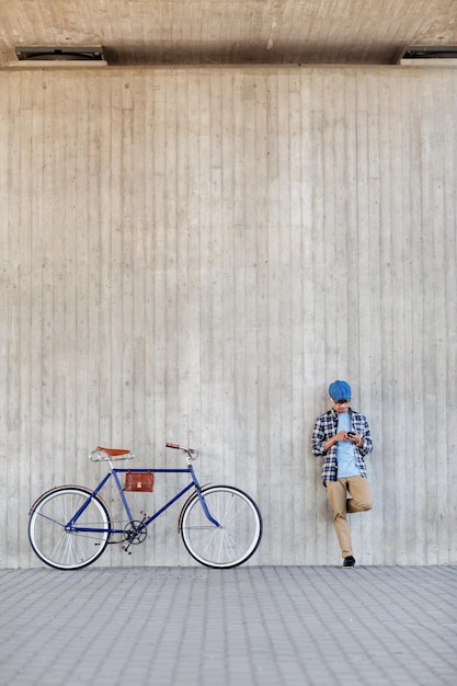 persone, comunicazione, tecnologia e stile di vita - uomo hipster con smartphone, auricolari e bici a scatto fisso che ascolta musica sulla strada della città