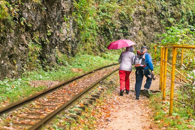 Persone con un ombrello camminano lungo la ferrovia