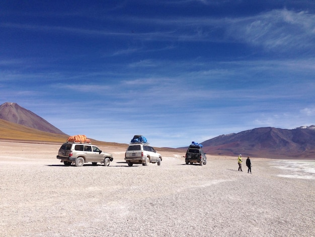 Persone con veicoli nel deserto contro il cielo