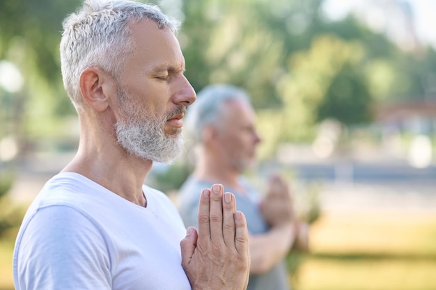 Persone di mezza età che fanno lezione di yoga nel parco