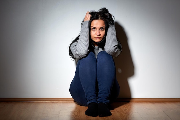 persone, dolore e violenza domestica concetto - donna infelice seduta sul pavimento e piangendo a casa