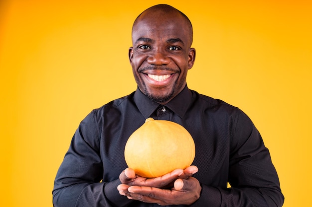 Persone e concetto di preparazione di Halloween uomo che tiene piccola zucca in studio sfondo giallo