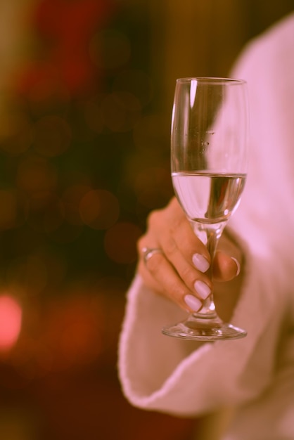 persone e concetto di relax bella giovane donna in accappatoio che beve champagne alla spa su sfondo di luci vacanze