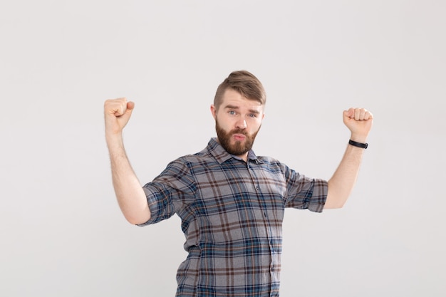 Persone, emozioni e concetto di vittoria - Divertente giovane uomo vestito con una camicia che mostra i pugni su bianco