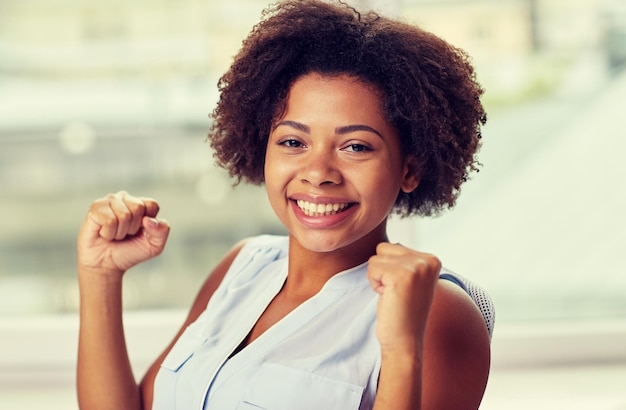 persone, emozioni, gesto e concetto di successo - felice giovane donna afroamericana con i pugni alzati