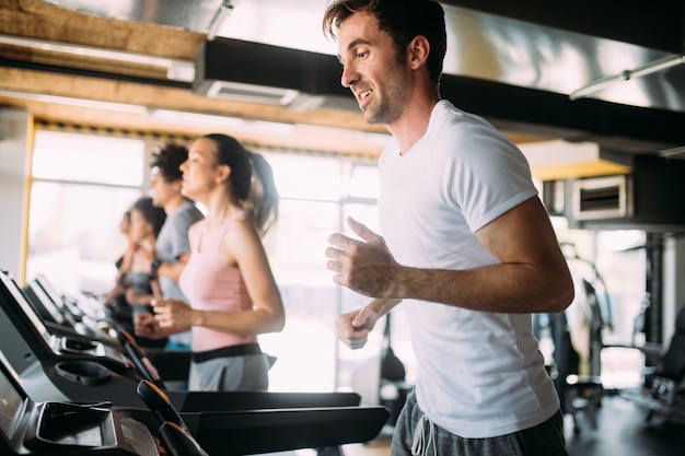 Persone felici in forma che corrono sul tapis roulant in palestra