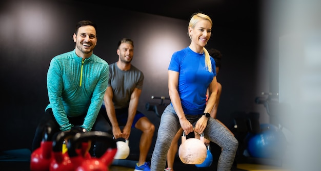 Persone felici in forma che si allenano durante la lezione di fitness in palestra